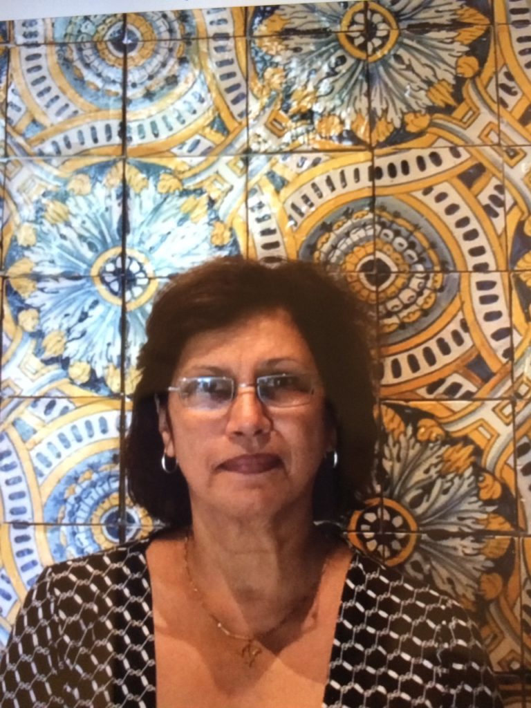 A photograph of Iris Lopez, a woman, in front of a mosaic tile wall, taken in Lisbon, Portugal.