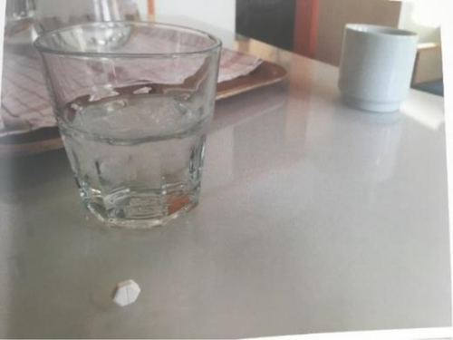 A table with a glass of water and a diamond-shaped pill.