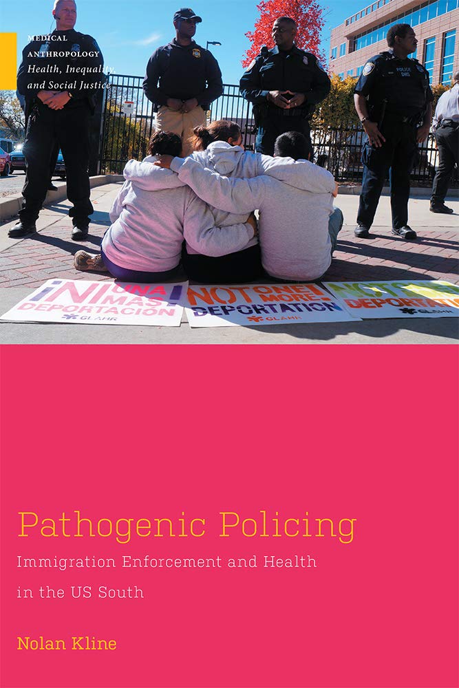 Cover, featuring the back shot of three protestors sitting with their arms around each other. They are facing four policemen standing in front of them