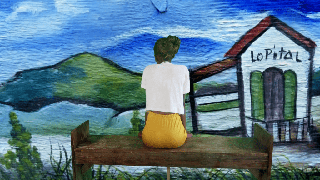 A woman sitting at a bench facing a mural of a colorful landscape with her back to the viewer.